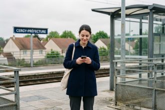 Jeune femme dans le train à Cergy regardant son téléphone